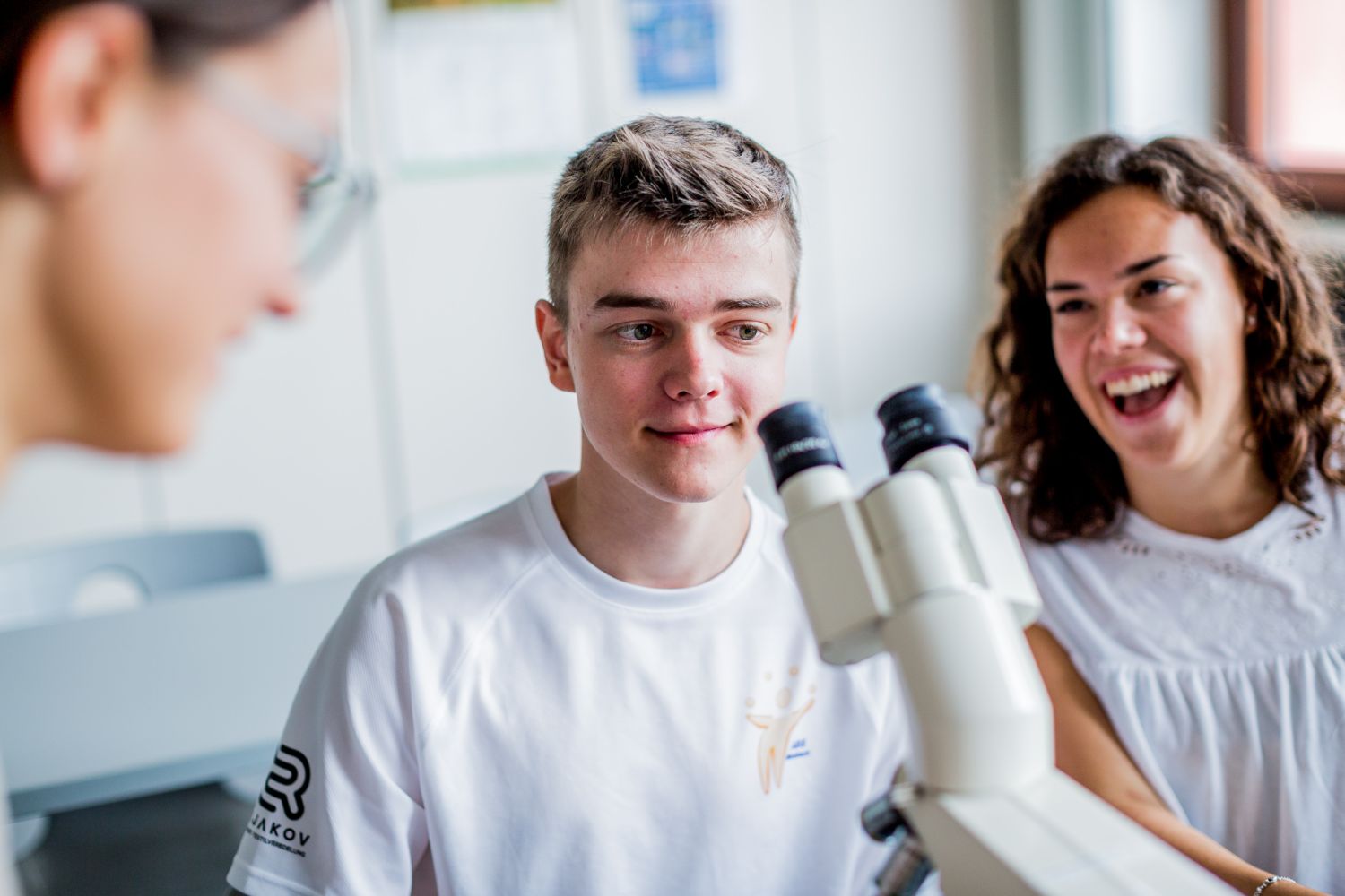 Auf dem Bild sieht man drei Personen mit einem Mikroskop. 
