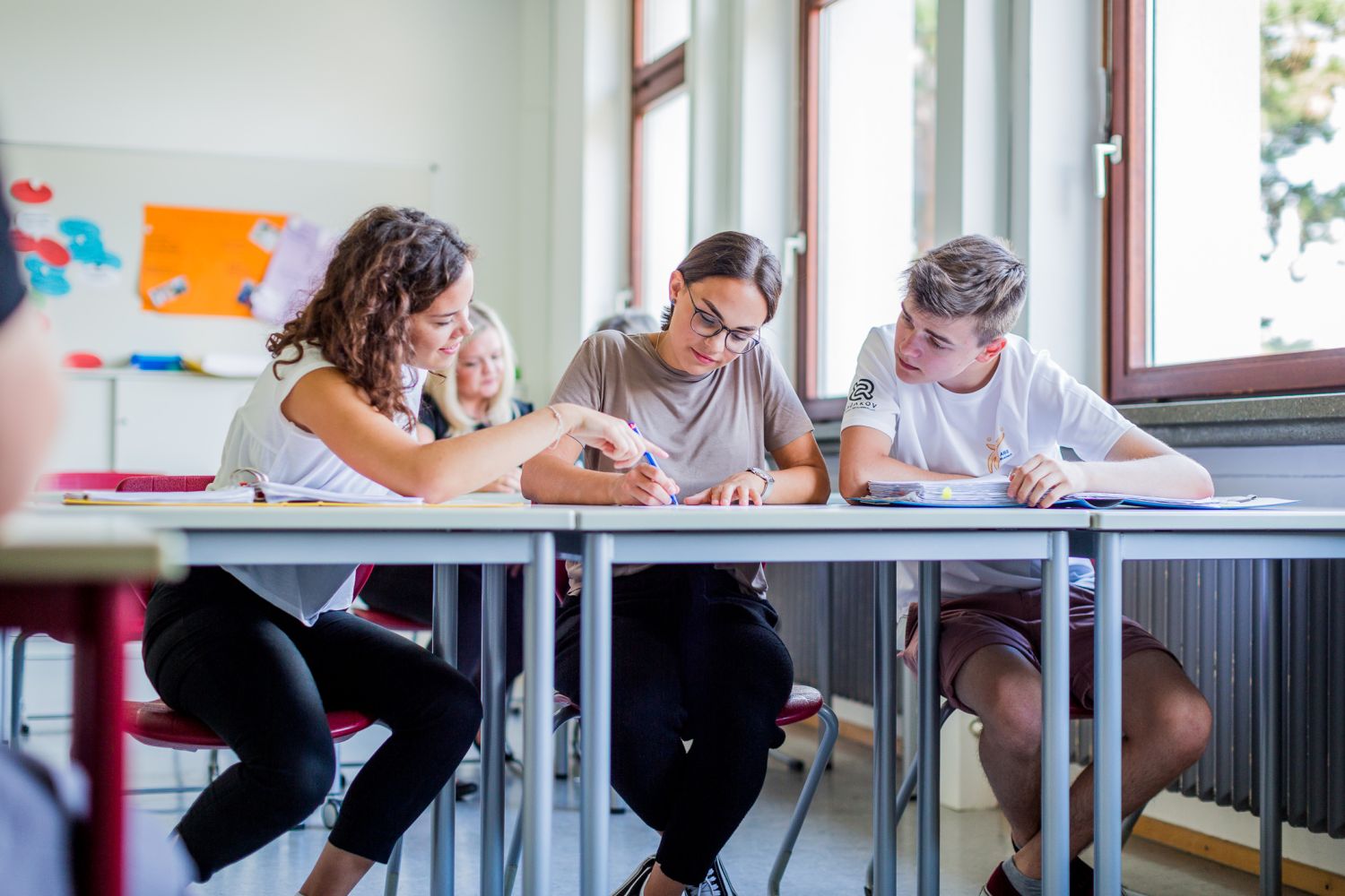 Mehrere Schüler diskutieren oder arbeiten an einer Aufgabe in ihrer Tisch.